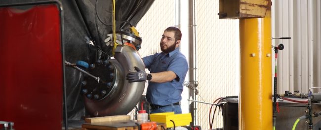 Close-up of a technician installing mechanical components on a reverse-engineered replacement pump.